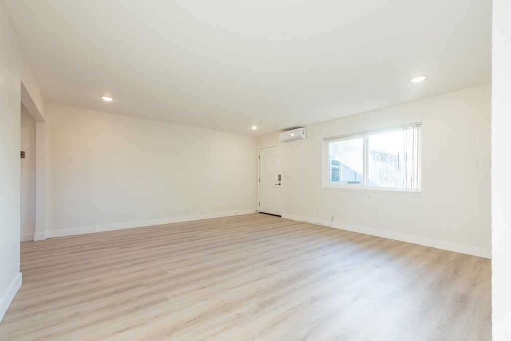 an empty living room with white walls and wood floors