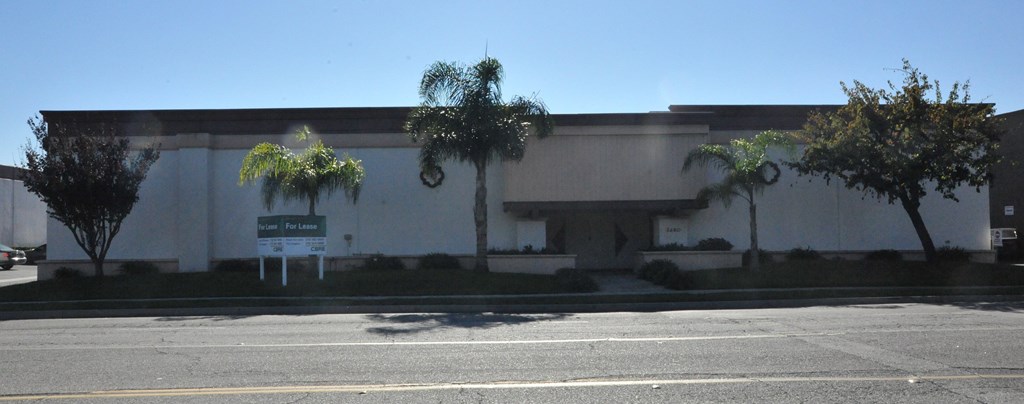 A building with a white facade and a green sign in front.