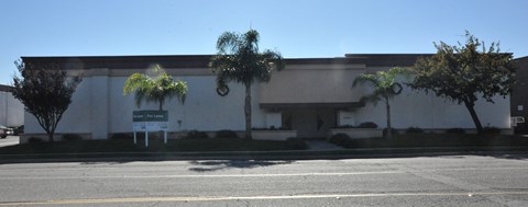 A building with a white facade and a green sign in front.