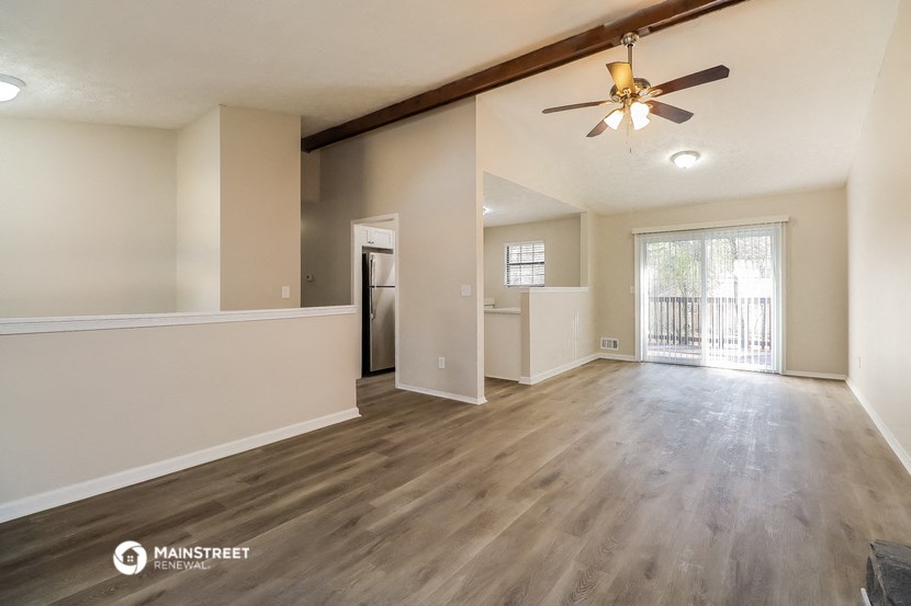 the living room and dining room of an empty house with a ceiling fan
