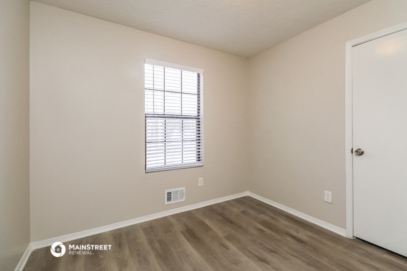 the spacious living room with hardwood flooring and a window