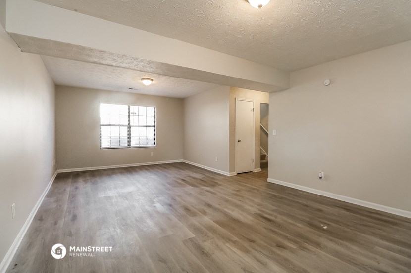 the spacious living room with hardwood flooring and a window