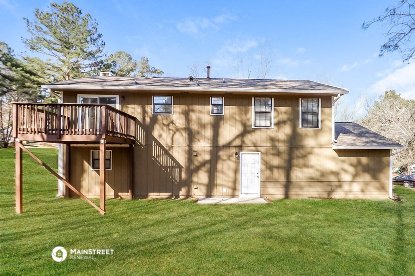 a tan house with a deck on top of a yard
