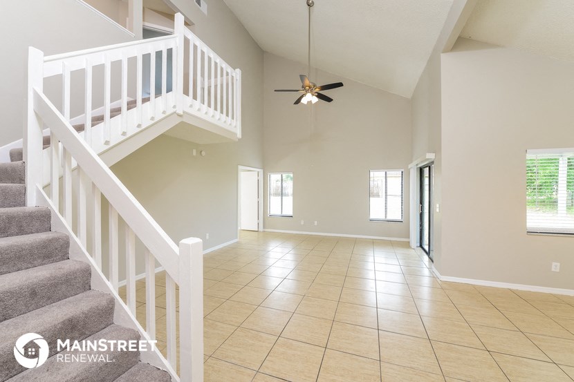 an empty living room with stairs and a ceiling fan