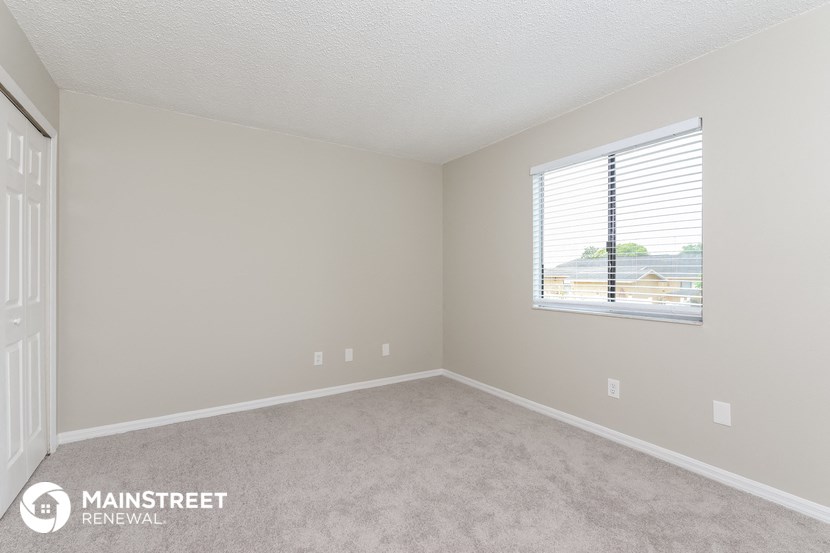 a bedroom with a large window and a carpeted floor