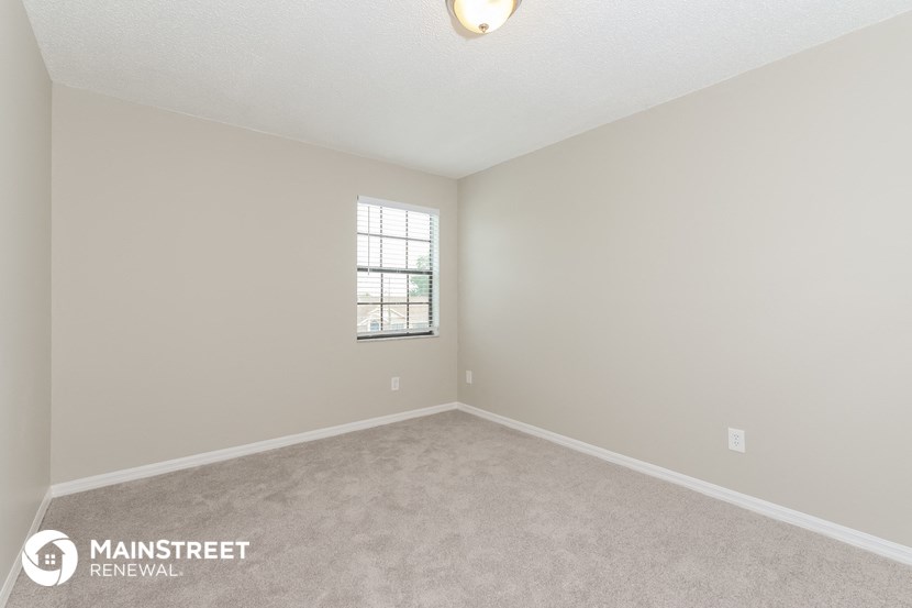 the spacious living room with carpeting and a window