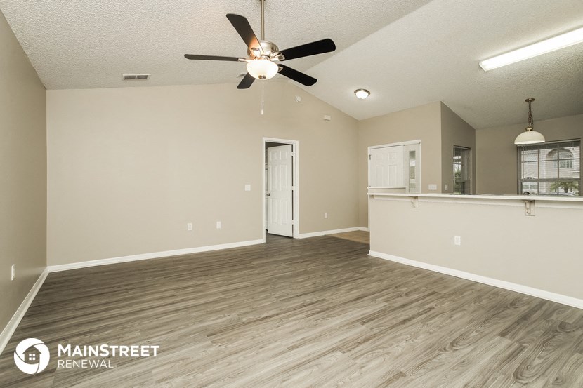 the spacious living room and kitchen of this manufactured home with a ceiling fan