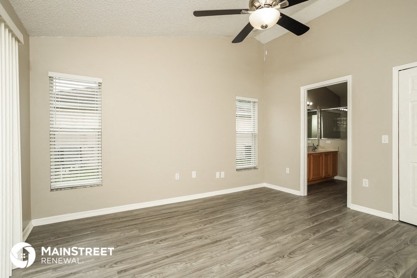 the spacious living room with a ceiling fan and wood flooring