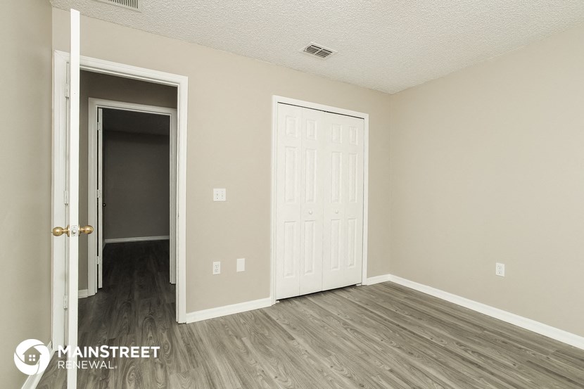 the living room of an apartment with wood floors and a white door