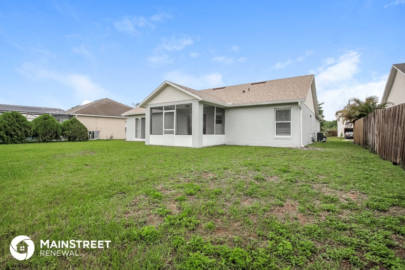the backyard of a home with a lawn and a fence