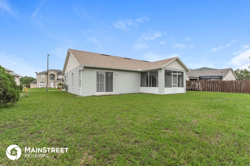 the backyard of a home with a lawn and a fence