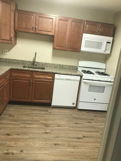 A kitchen with white appliances and wooden cabinets.