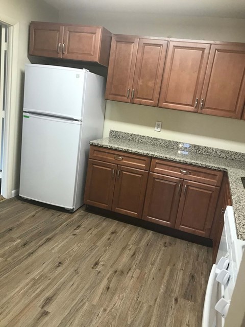 A white refrigerator in a kitchen with wooden cabinets.