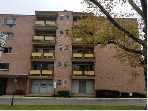 A tall apartment building with a sign that says "NO PARKING".