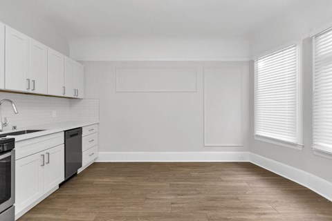 A kitchen with white cabinets and a wooden floor.