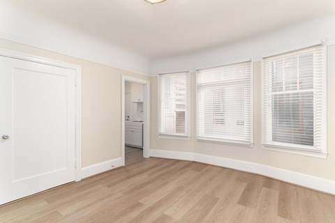 A room with a white door, a window with blinds, and a washing machine.