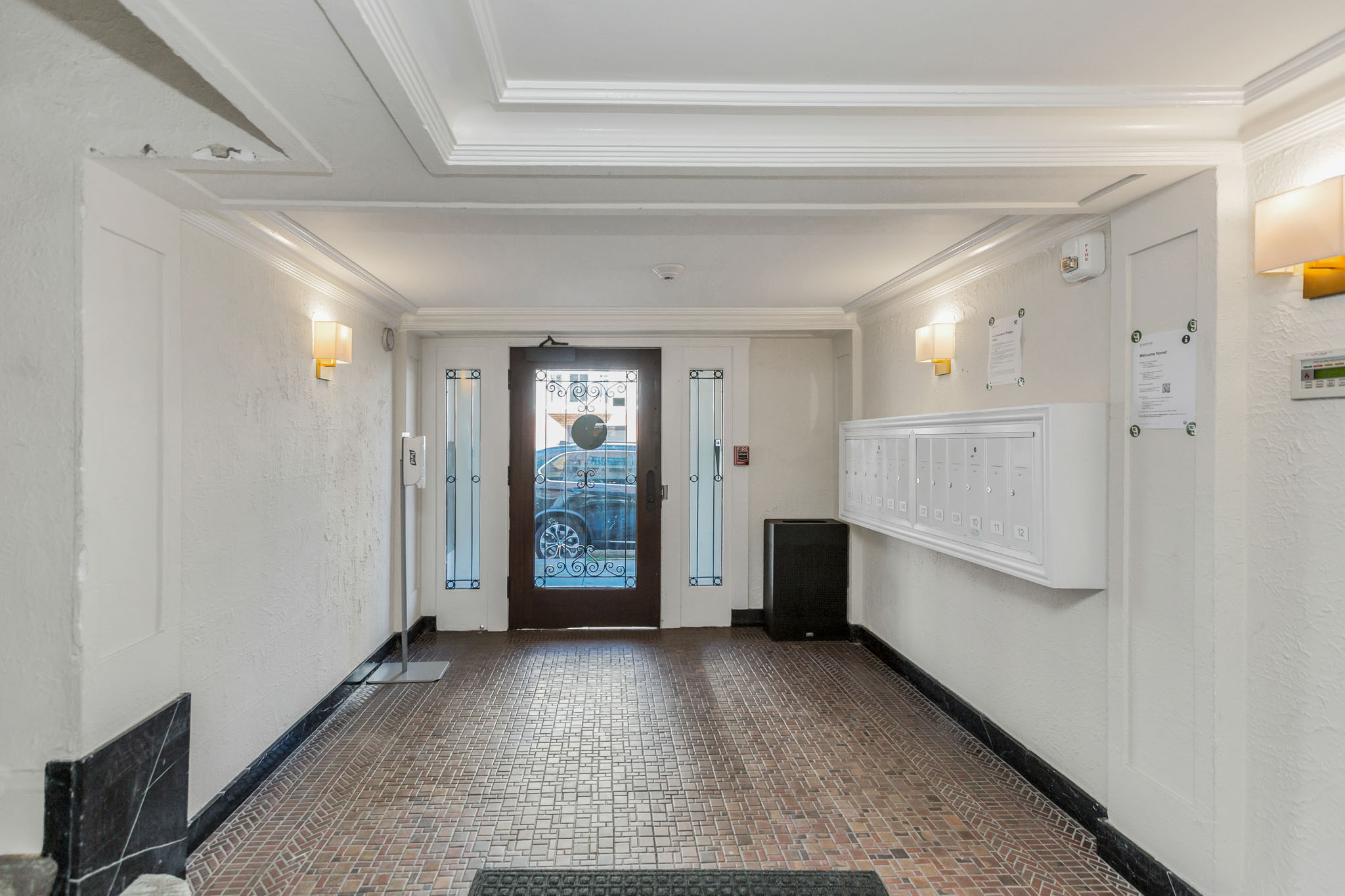 A hallway with a tiled floor and a black speaker on the floor.