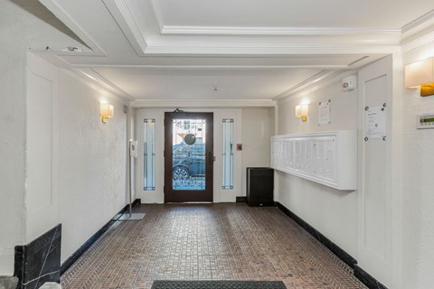 A hallway with a tiled floor and a black speaker on the floor.