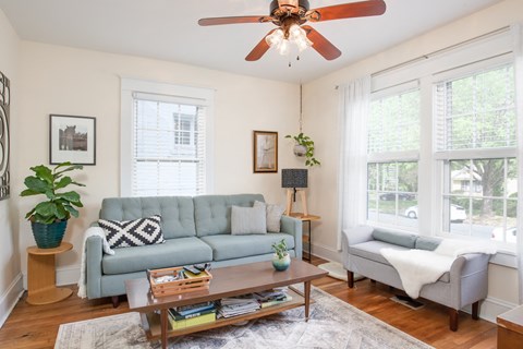A living room with a green couch and a ceiling fan.