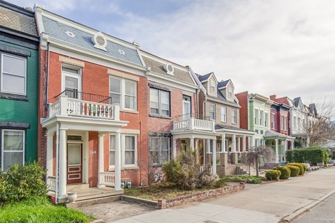 A row of houses with green, red, and brown facades.