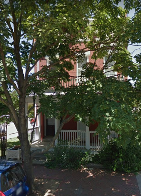 A tree in front of a red building.