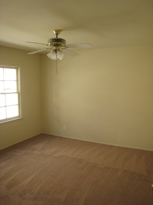 a empty room with a ceiling fan and a window