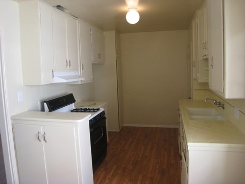 an empty kitchen with white cabinets and a stove