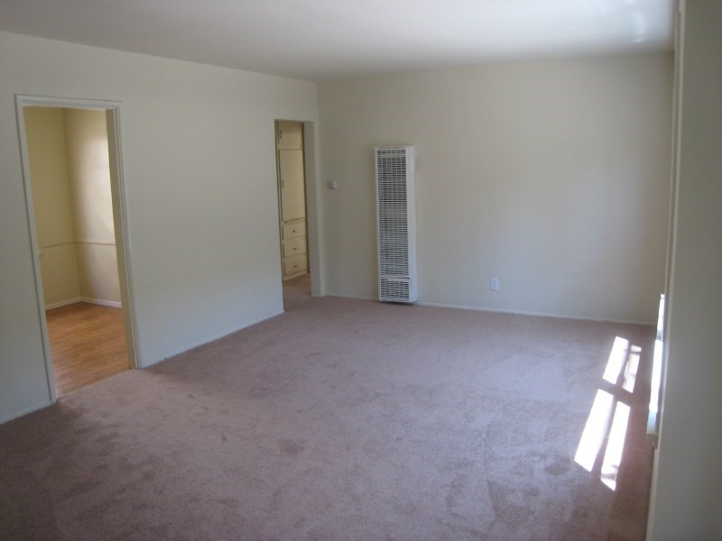 an empty living room with white walls and a wood floor