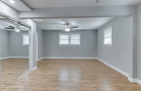 an empty living room with wood floors and a ceiling fan