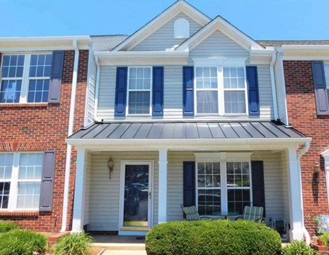 A house with a white front porch and black shutters.