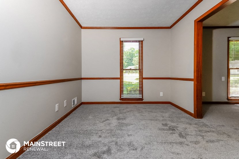 the living room of a house with carpet and a window