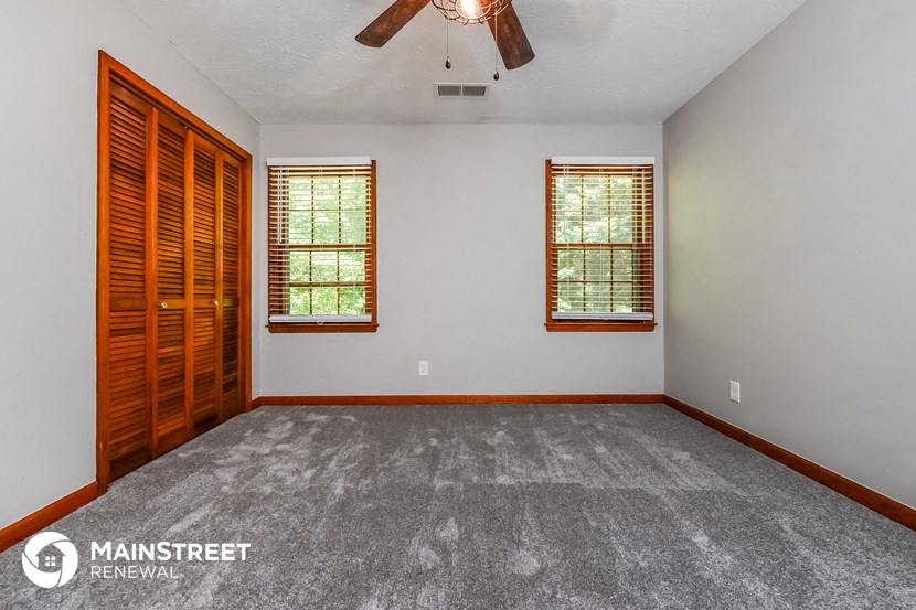 the master bedroom is spacious and clean with a ceiling fan and two windows