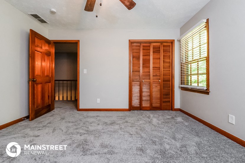 an empty living room with carpet and a wooden door and window