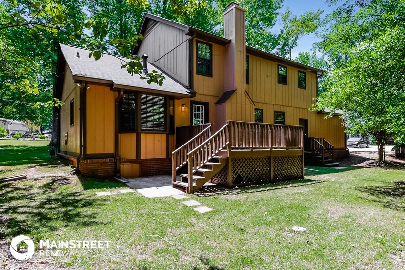 the front of a yellow house with a porch and a wooden deck