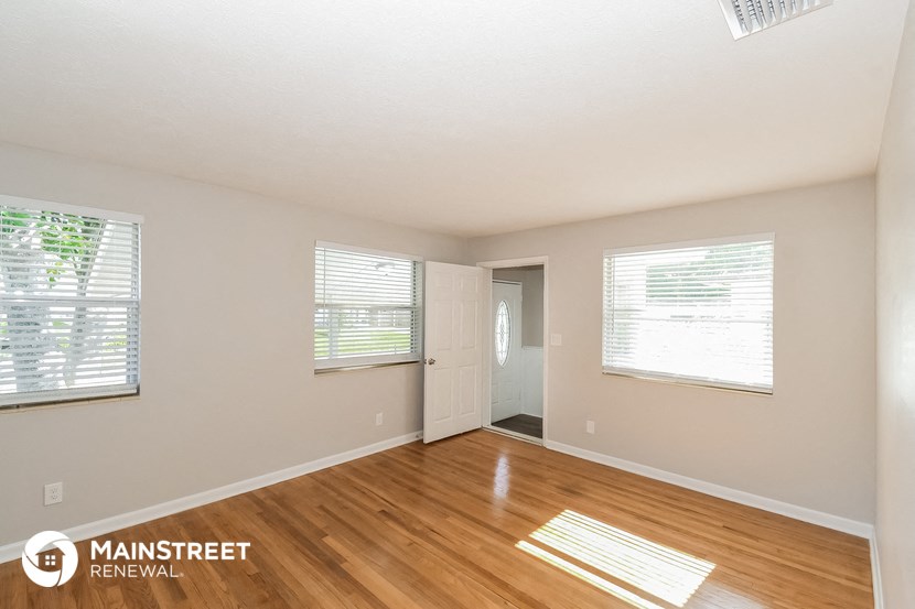 a living room with a hardwood floor and a door to a hallway