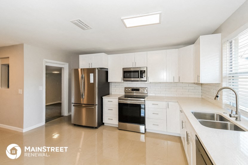 a large kitchen with white cabinets and stainless steel appliances