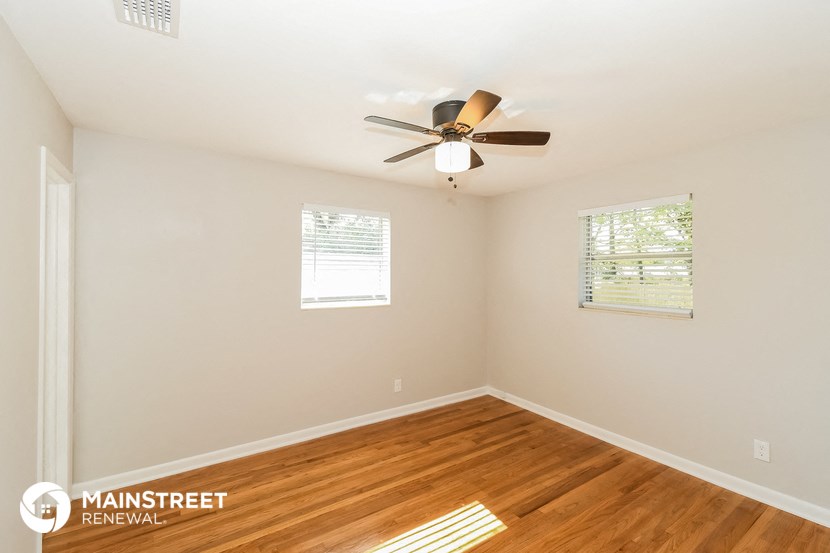 a bedroom with a ceiling fan and a wood floor