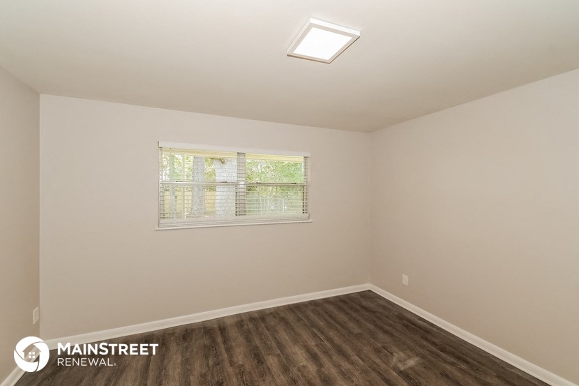 an empty room with a window and wood flooring