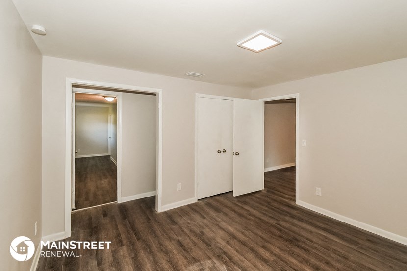 a bedroom with a wood floor and white walls and a closet