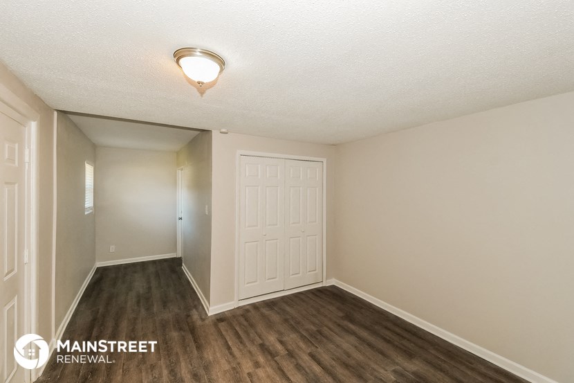 the spacious living room of a manufactured home with wood flooring and a white door