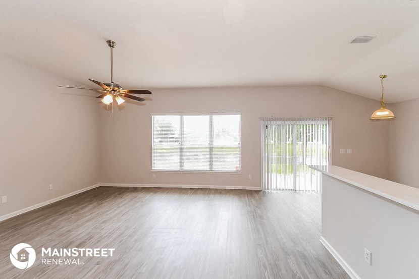 an empty living room with a ceiling fan and a window