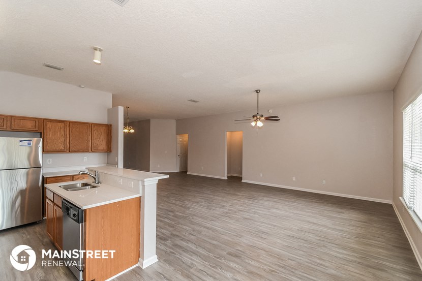 an open kitchen and living room with wood flooring and a ceiling fan