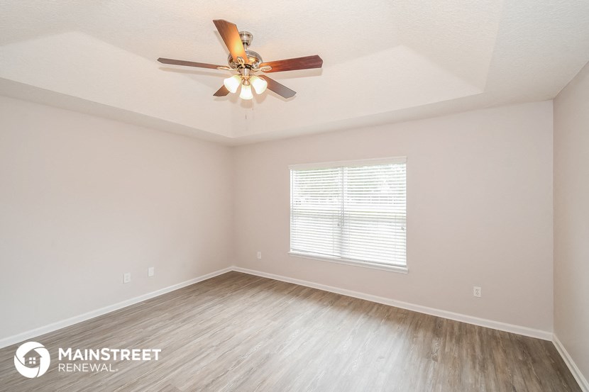 the spacious living room with ceiling fan and wood flooring