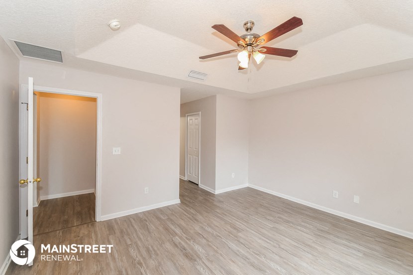the spacious living room with ceiling fan and wood flooring