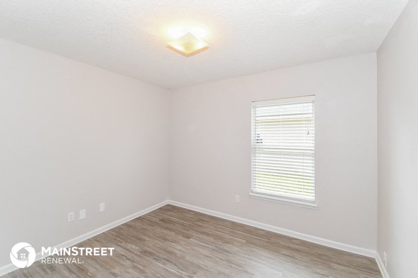 the interior of a white room with wood flooring and a window