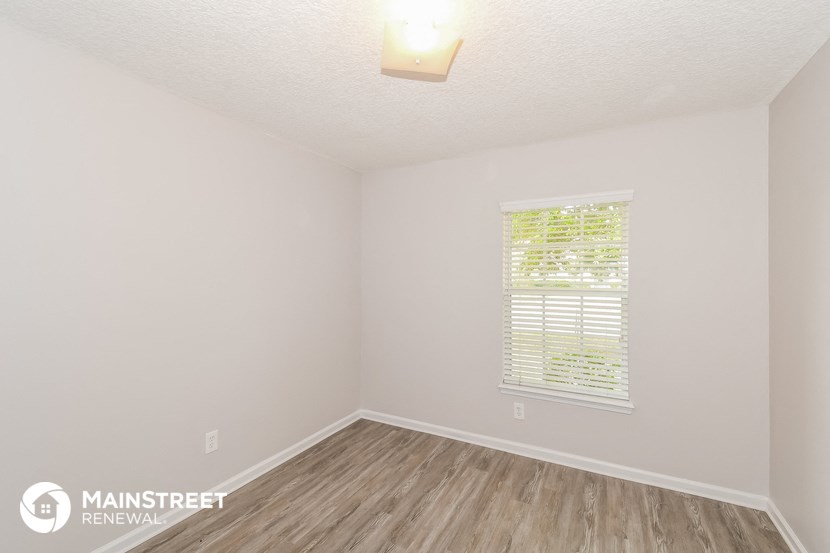 the upstairs bedroom with wood floors and white walls and a window
