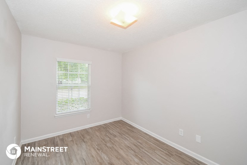 the spacious living room with wood flooring and white walls