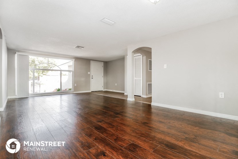 an empty living room with wood flooring and a large window