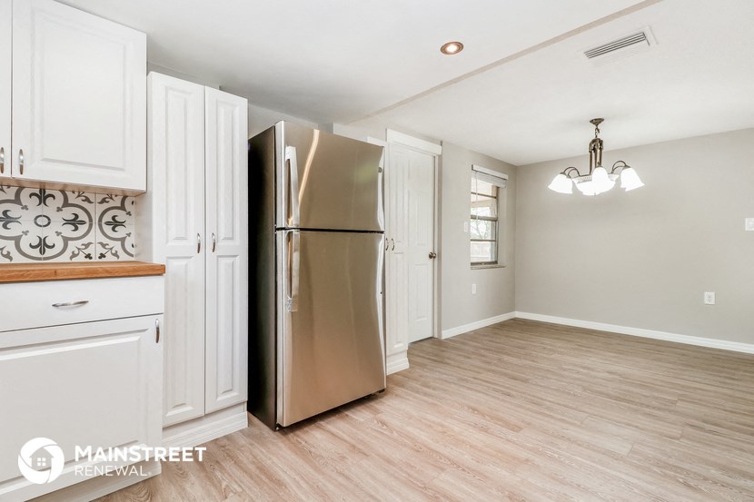 a kitchen with white cabinets and a stainless steel refrigerator
