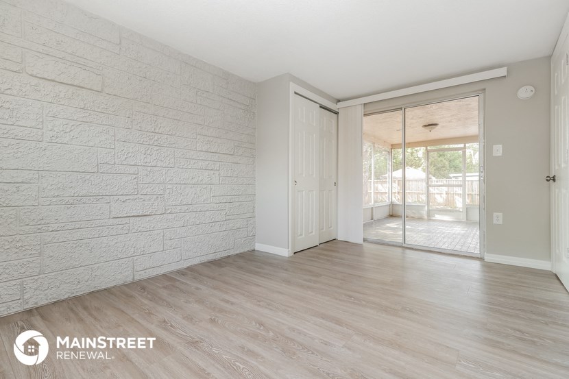 the living room of an apartment with wood floors and a white brick wall